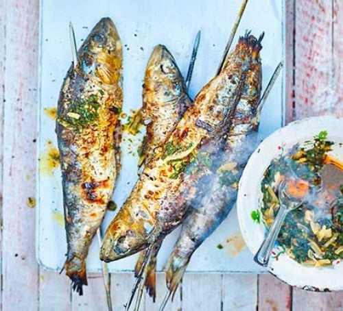Barbecued sardines on sticks with green chermoula sauce