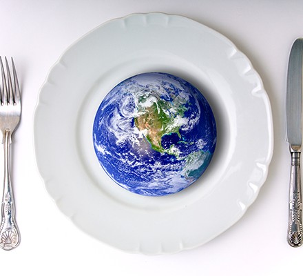 An image of planet Earth on a plate with a knife and fork alongside it