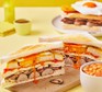 The breakfast club sandwich Two breakfast club sandwiches with a bowl of beans alongside
