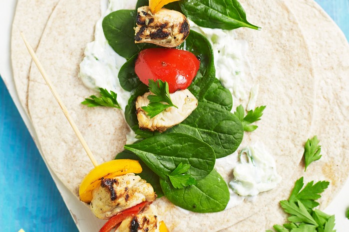 Chicken skewers with tzatziki Chicken and vegetables on open tortilla wraps