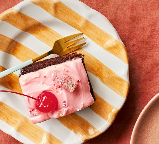 A square of chocolate cherry cola cake on a striped plate
