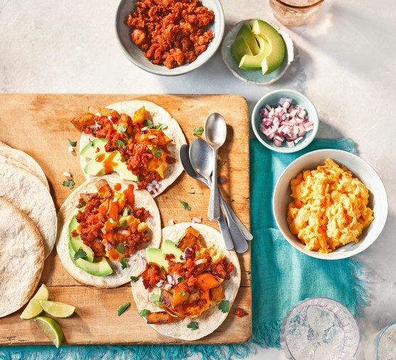 A board of tortillas topped with eggs, sweet potato and avocado