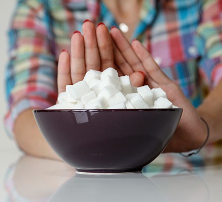 A woman holding out her hands to say no to a bowl of sugar
