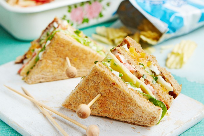 Egg-&-cress-club-sandwich Two egg and cress club sandwiches on a plate in front of some crisps