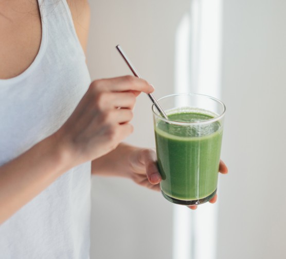 Hands holding a green juice for a healthy cleanse diet