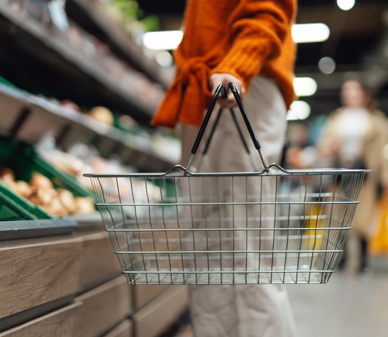 Money-saving tips for your weekly shop Young woman carrying a shopping basket while shopping in supermarket