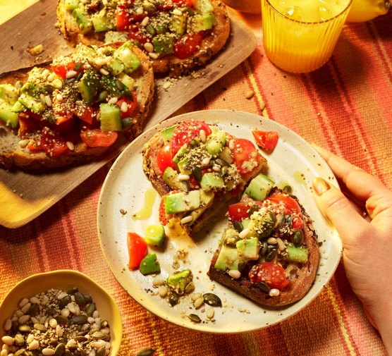 Avocado and tomato sits on top of sourdough toast.