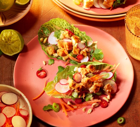 Crispy tofu sits in a boat of lettuce with vegetables and dressing