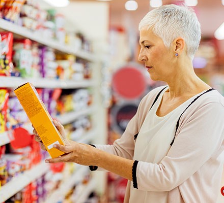 A woman reading a food label in a supermarket