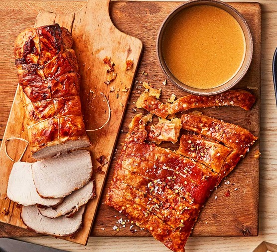 Herb-roasted pork in milk with crackling on a wooden serving board