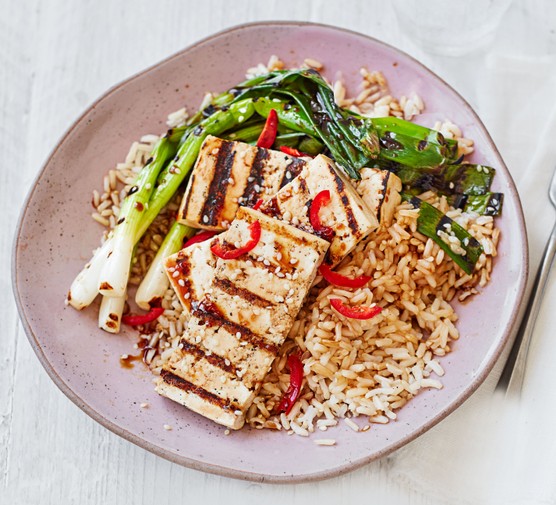 Charred spring onions and tofu blocks on a plate
