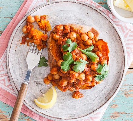Low-salt lunch recipes Vegan chickpea curry jacket potato on a plate with a slice of lemon and fork alongside