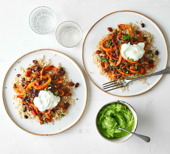 Five bean chilli Two plates of veggie bean chilli topped with cream and served with green sauce